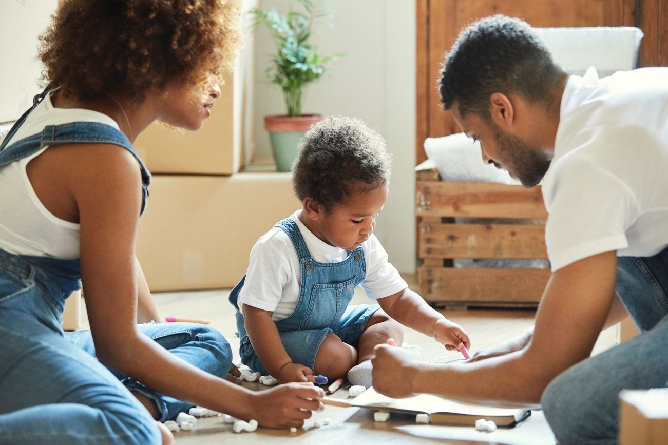 Parents with daughter drawing in new apartment
